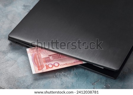 One hundred yuan sticking out of a laptop, concept on the theme of remote work Royalty-Free Stock Photo #2412038781