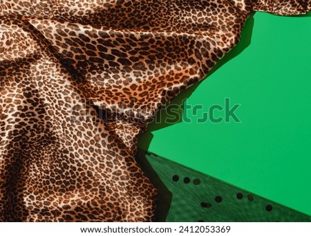 Glamorous, chic leopard skin printed fabric combined with emerald green background and black polka dot tulle, creative copy space.