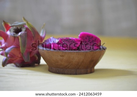 Ripe Red Meat Dragon Fruit served in Cubes in the wooden bowl or Pink Pitaya with Whole Fruits on the rustic wooden board with copy space