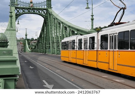 Yellow tram on a green suspension bridge, a tram rides on a metal bridge, Budapest Liberty Bridge, a yellow tram, a bridge over the Danube Royalty-Free Stock Photo #2412063767
