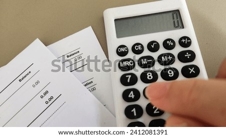 A person pressing calculator with statement showing zero balance 