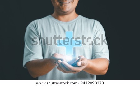 Mental health care mental rejuvenation concept. Man smiling good mood hand holding virtual blue plus sign for positive thinking mindset or healthcare insurance symbol. Royalty-Free Stock Photo #2412090273