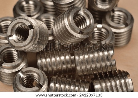 Stainless steel fine thread wood insert. Composite and polymer panels threaded insert. Internal 1 4-20 NC threaded insert. Closeup of stainless steel insert Royalty-Free Stock Photo #2412097133