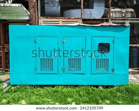 A weatherproof enclosed commercial backup generator for a business establishment. Placed at the back of the building. Royalty-Free Stock Photo #2412105749