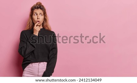 Photo of impressed young woman keeps mouth opened from wonder reacts to something amazing dressed in casual clothes feels stunned isolated over pink background copy space for your advertising content
