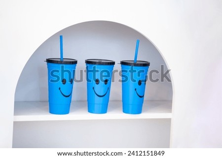 Cute blue plastic glasses with smiley faces placed on a white cabinet shelf.