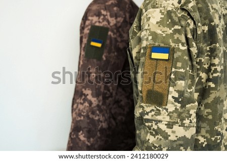 Two ukrainian soldiers in pixel military uniform with flag of Ukraine banner on shoulder