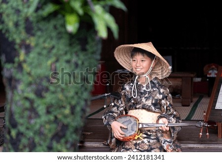 boy wearing Okinawan folk costume and drawing a sanshin line Royalty-Free Stock Photo #2412181341