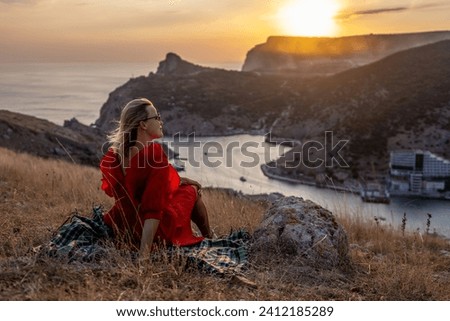 Woman sunset sea mountains. Happy woman siting with her back on the sunset in nature summer posing with mountains on sunset, silhouette. Woman in the mountains red dress, eco friendly, summer