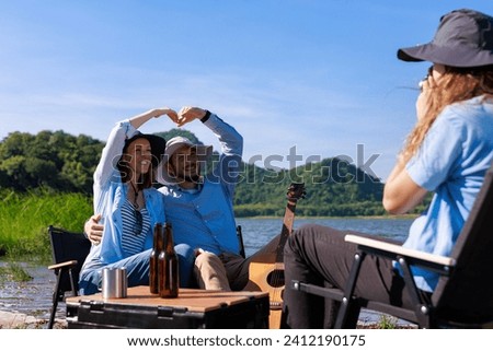 happy family daughter takes pictures for mom and dad  at the campground by the riverside, mountain and blue sky background,
