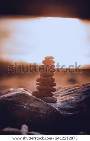 A stack of stones made at the beach with the setting sun as a background in the evening. Taken at Khorfakkan beach shark island.