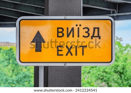 emergency exit sign in yellow board hanging on a ceiling. Ukrainian sign: Exit