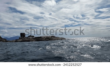 The dark blue sea in front of mountain island and rock island under the delicate multi layers cloud sky background 