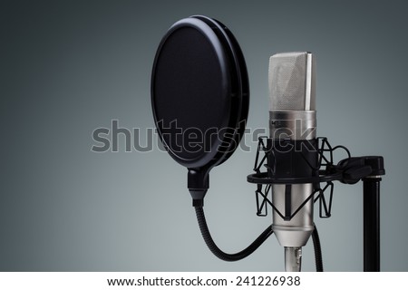 Studio microphone and pop shield on mic stand against gray background Royalty-Free Stock Photo #241226938