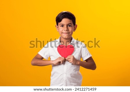 Portrait of kid boy holding paper heart. Love and valentine day and gratitude concept