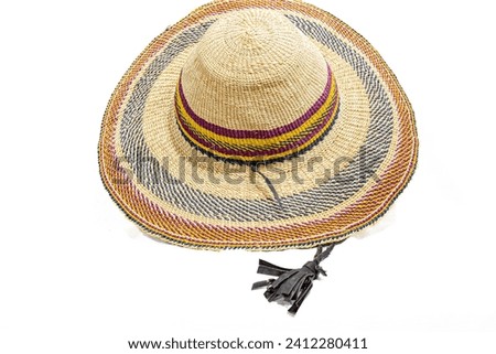 A straw hat with yellow, red and bluish grey stripes and a black hanging leather filaments accessory. Studio shot isolated in white background. High quality high angle oblique view photograph. 