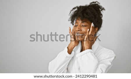 African american woman wearing bathrobe massaging face over isolated white background