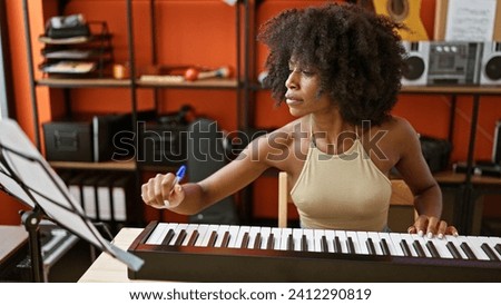 African american woman musician playing piano reading music sheet at music studio Royalty-Free Stock Photo #2412290819