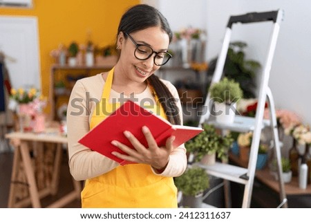 Young arab woman florist smiling confident writing on notebook at flower shop
