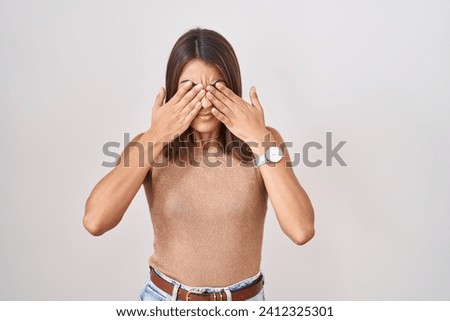 Young hispanic woman standing over white background rubbing eyes for fatigue and headache, sleepy and tired expression. vision problem 