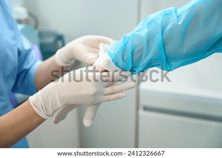 Cropped of nurse helping male doctor put on latex glove on hand before surgery