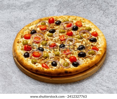 Homemade Italian style pizza with cheese, olives and black olives, onions, cherry tomatoes and minced meat close-up on a wooden board on the table. Horizontal