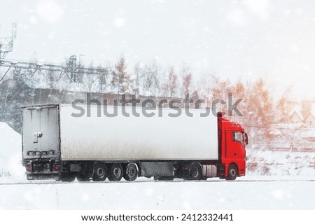 Semi truck on the winter road. A big industrial truck delivering goods in cold weather after the snow storm. Royalty-Free Stock Photo #2412332441