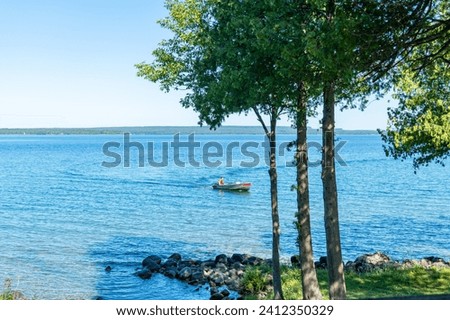 View to the beautiful Lake Manitou from the cabin. Amazing sky line landscape with trees and water. Canadian wilderness. Perfect spot for a holiday. Cottage located on the largest fresh water island. Royalty-Free Stock Photo #2412350329