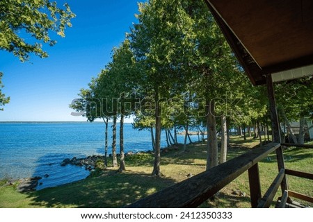View to the beautiful Lake Manitou from the cabin. Amazing sky line landscape with trees and water. Canadian wilderness. Perfect spot for a holiday. Cottage located on the largest fresh water island. Royalty-Free Stock Photo #2412350333