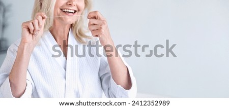 Web banner, panoramic view of woman in robe with dental floss in hands. Toothcare routine. Female flossing healthy teeth over white studio background, copy space. Royalty-Free Stock Photo #2412352989