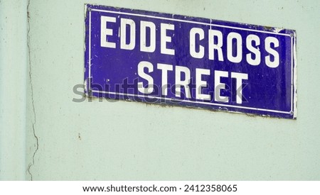 Street name sign; Edde Cross Street which runs north - south from the junction between the High Street and Wilton Road. A bluue sign, with white letters on a pale green wall.