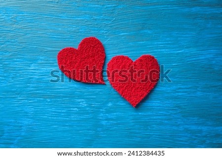 Plush red hearts on a textured light blue table.