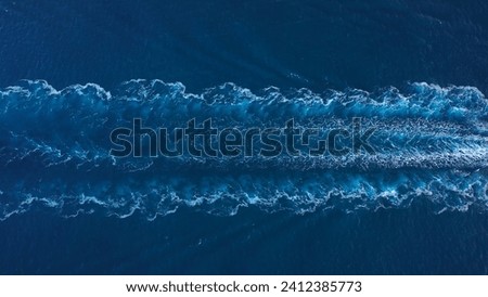 Prop wash of a tanker ship underway open sea. Aerial top down drone view of water foam trace behind a crude oil tanker Royalty-Free Stock Photo #2412385773