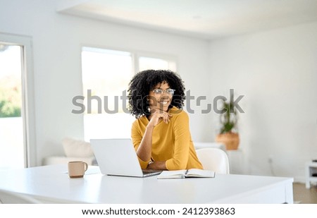 Happy young African American lady sitting at home table and looking away while hybrid working or learning using laptop computer, smiling woman looking away thinking drinking coffee in living room. Royalty-Free Stock Photo #2412393863