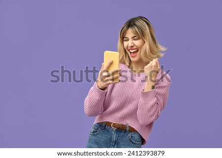 Excited crazy gen z blonde young woman winner with smartphone, happy shopper customer student girl screaming yes using mobile cell phone celebrating online prize win on purple background. Royalty-Free Stock Photo #2412393879