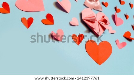 Pink paper hearts, origami, arranged on a light background. Top 