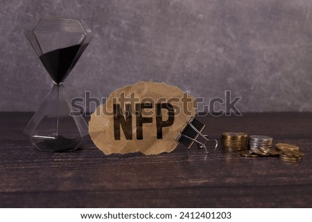 Selective focus of pens, clock, money banknote and notebook written with text NFP stands for Nonfarm payrolls. Business concept.