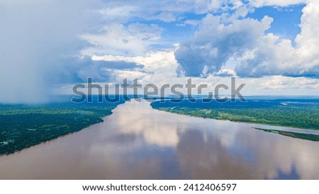 Aerial view of the tranquil Amazon River, surrounded by lush greenery under a cloudy sky in Leticia, Amazonas, Colombia Royalty-Free Stock Photo #2412406597