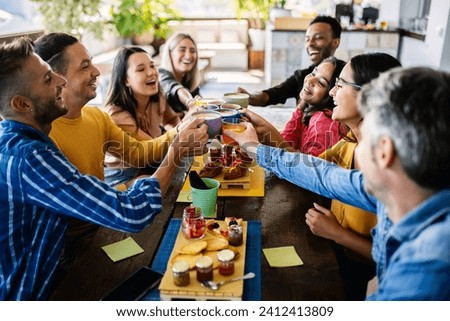 Smiling multiracial group of young people having breakfast together at coffee eatery shop Royalty-Free Stock Photo #2412413809