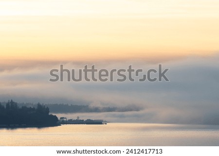 The Mukilteo Ferry dock peaks through the fog on the puget sound on a foggy winter afternoon Royalty-Free Stock Photo #2412417713