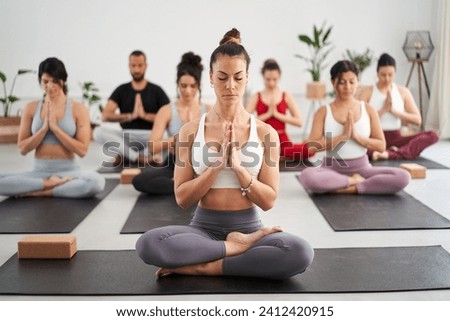 Group diverse fitness young people practicing yoga mudra exercises in class, asana posture with eyes closed. Concentrated meditating women and man in sportswear. Healthy and wellness in community. Royalty-Free Stock Photo #2412420915