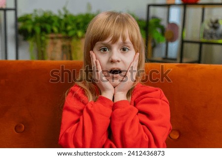 Oh my God, Wow. Caucasian surprised preteen school girl looking at camera with big eyes, shocked by sudden victory, good win news, celebrating. Excited amazed child kid at home living room on couch