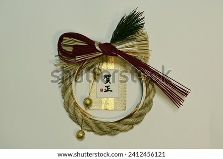 Japanese New Year decoration, a sacred rope of rice-straw, pine needles, paper strap of red and white for celebration. Translation: "A Happy New Year".