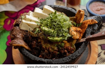A view of a molcajete platter on a table with nachos and salsa Royalty-Free Stock Photo #2412459927