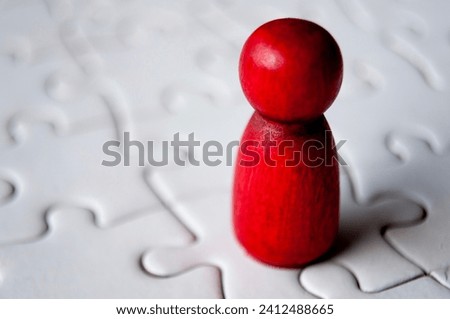 A single red wooden doll on jigsaw puzzle.
