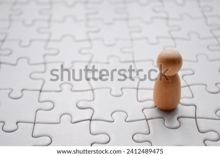 A wooden doll on white jigsaw puzzle. Loneliness concept.
