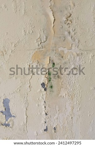 Badly fixed building facade wall covered with cracks in paint. Missing patch of paint in the middle; crack with flappy peeling edges. vintage background Royalty-Free Stock Photo #2412497295