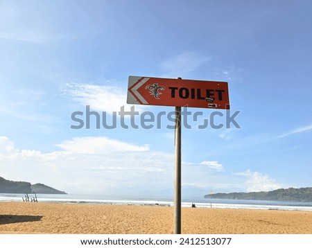 Toilet sign on the beach. Wooden sign pointing to the ladies and gents toilets.