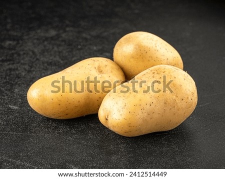 Three raw potatoes on grey background Royalty-Free Stock Photo #2412514449