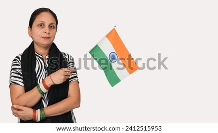 A young Indian lady carrying a national small flag with patriotic feeling, wearing tricolor glass bangles on her hand, during the 26 January celebration, with a happy mood, isolated in the background. Royalty-Free Stock Photo #2412515953